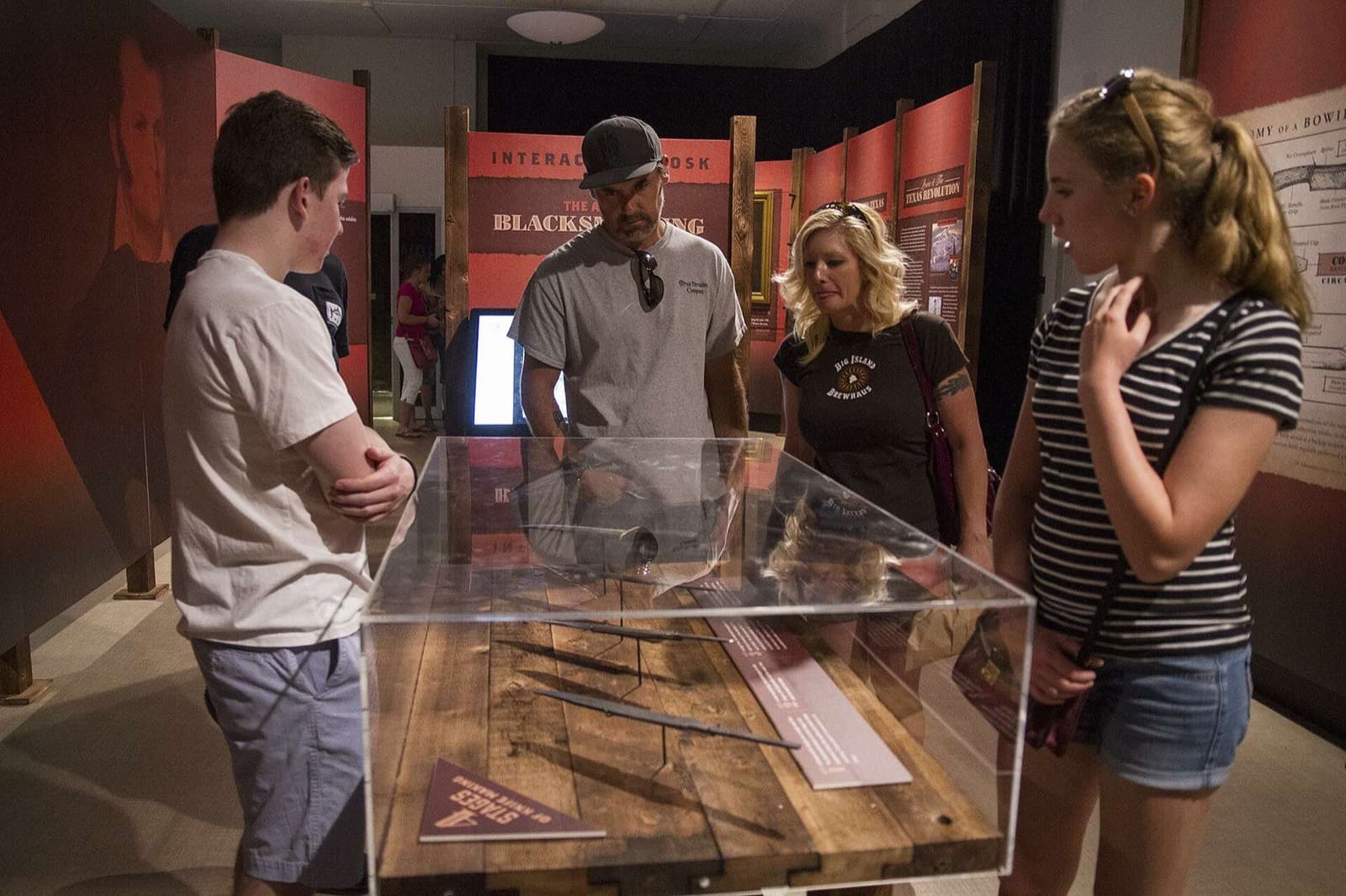 A family gathered around a lit case at the blacksmithing interactive station.